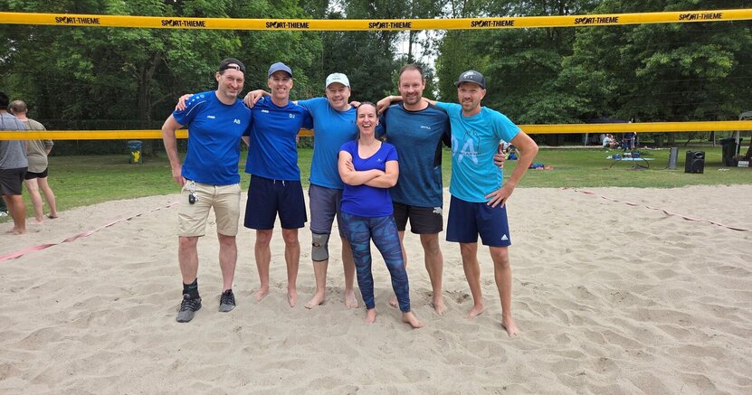 Die Vorjahressieger „Fürst von Schmetternicht“ wollen ihren Titel verteidigen Das Team von "Fürst von Schmetternicht" stehen in blauen T-Shirts auf dem Sand eines Beachvolleyball-Feldes. Im Hintergrund sind die Liegewiese des Freibads Goddelau und Bäume zu sehen.