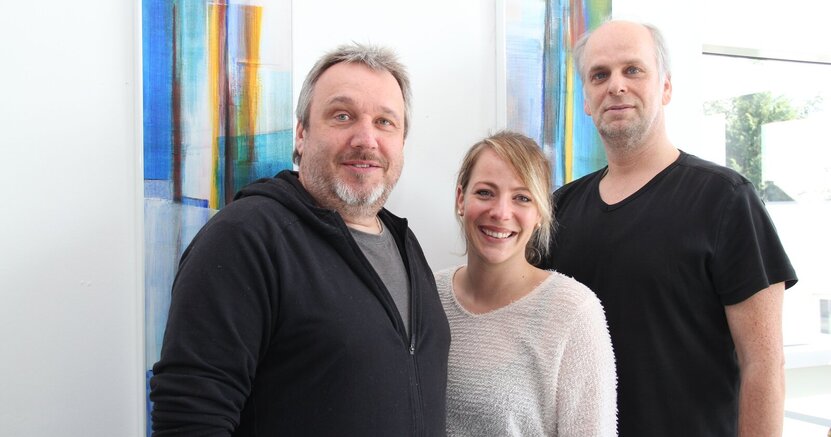 Die Drei vom Riedstädter Jugendbüro suchen Unterstützung: Kai Faßnacht, Julia Spitzer und Heiko Wambold (v.l.n.r) Kai Faßnacht, Julia Spitzer und Heiko Wambold (v.li.) vom Jugendbüro stehen vor einer weißen Wand mit buntem Wandbehang.