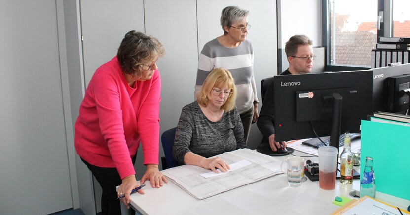 In verschiedenen Räumen des Rathauses werden die Stimmzettel ausgewertet. Hier Alexandra Hartmann, Cornelia Anthes, Bärbel Fischer und Peter Kraus (v.li.) Cornelia Anthes sitzt in einem Raum des Rathauses am Tisch und hat einen Stimmzettel vor sich liegen. Alexandra Hartmann steht neben ihr und schaut auch auf den Zettel. Daneben sitzt Peter Kraus und gibt Zahlen in den PC en, Bärbel Fischer steht hinter ihm und schaut, was er eingibt.