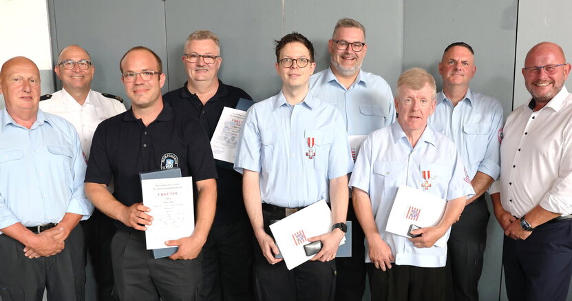 Die geehrten Feuerwehrleute stehen in schwarzer oder hellblauer Dienstkleidung in einer Reihe und halten ihre Urkunden in den Händen. Umgeben sind sie vom stellvertretenden Stadtbrandinspektir Peter Wendel, Kreisbrandinspektor Friedrich Schmidt, Stadtbrandinspektor Markus Kölsch sowie Bürgermeister Marcus Kretschmann