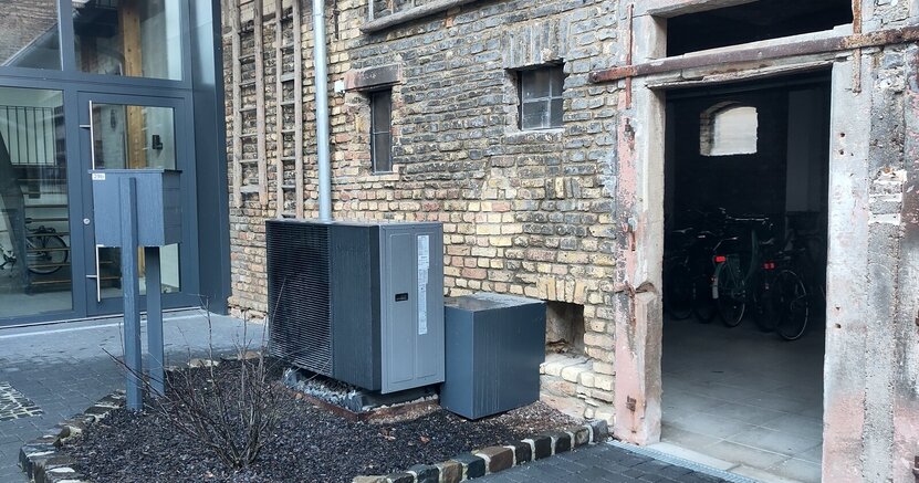 Wärmepumpen können auch im Altbau effizient funktionieren, wissen die Ver-anstalter. Vor der Außenwand eines Hauses steht eine Wärmepumpe.