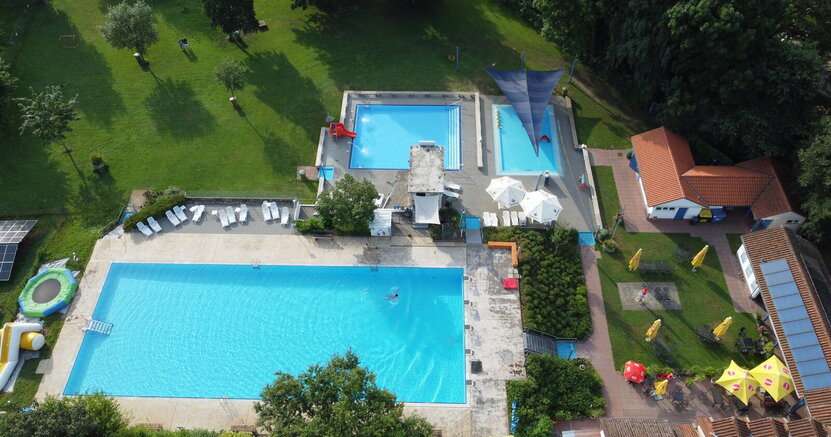 Bis einschließlich 9. September wurde die Saison im Freibad Goddelau verlängert. Von oben sind die frei Becken des Freibads Goddelau und die Liegewiesen mit Bäumen zu sehen. Im Vordergrund ist das große Schwimmerbecken mit einem Schwimmer. Dahinter das kleinere Nichtschwimmerbecken und das noch kleinere Planschbecken.